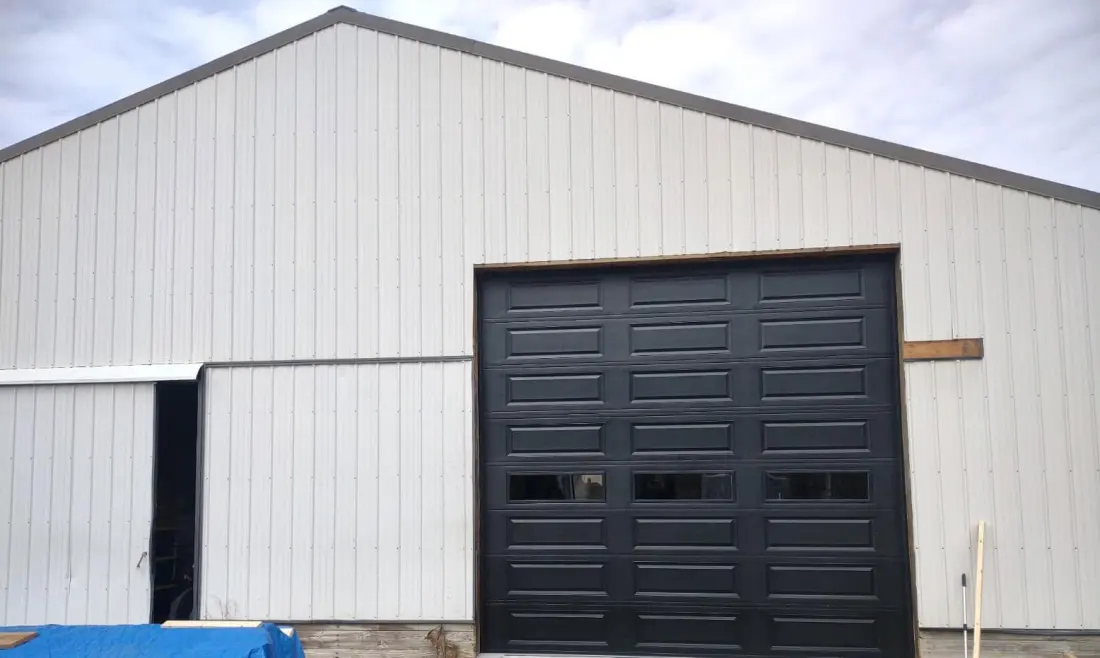 Large black commercial sectional door with a row of windows
