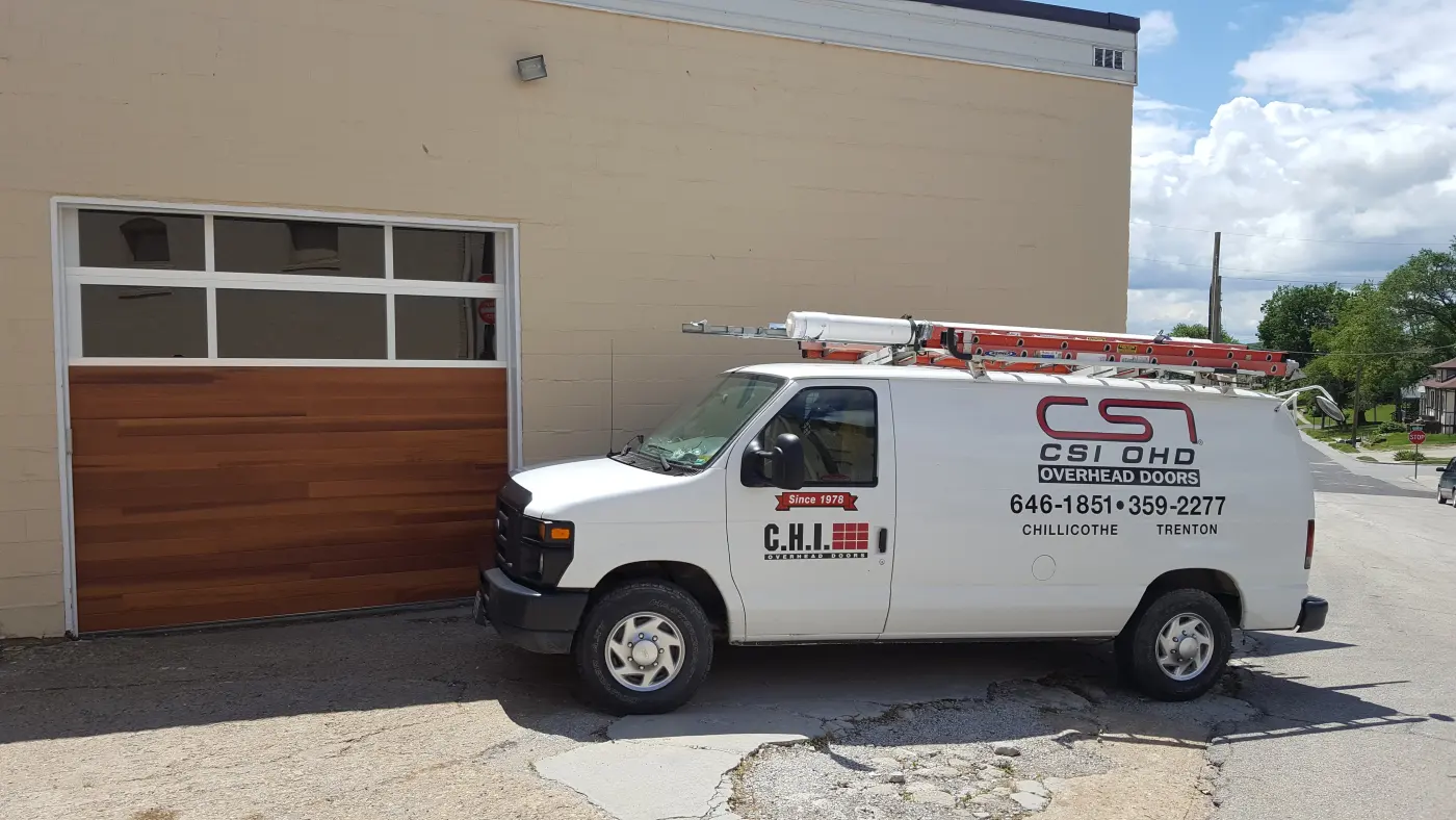 CSI OHD service van beside a wood-look garage door